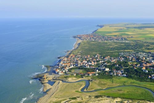 Vue aérienne d'un village côtier français avec falaises, plages et terres agricoles vertes le long de la Manche