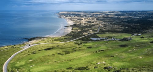 Vue aérienne du Domaine De La Ronville : paysage côtier verdoyant avec collines ondulantes, plages de sable et sinuosités