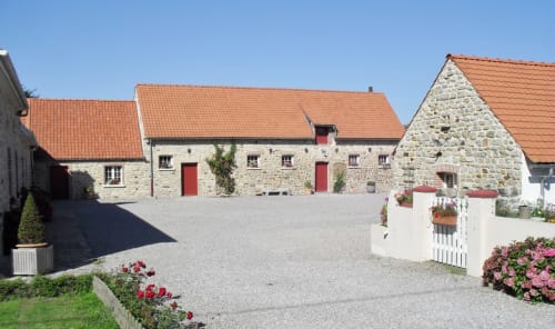 Domaine De La Ronville stone buildings with terracotta roofs, white gate, and flowering gardens in French countryside