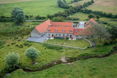 Domaine De La Ronville bed and breakfast with terracotta roof nestled in lush French countryside surrounded by green fields