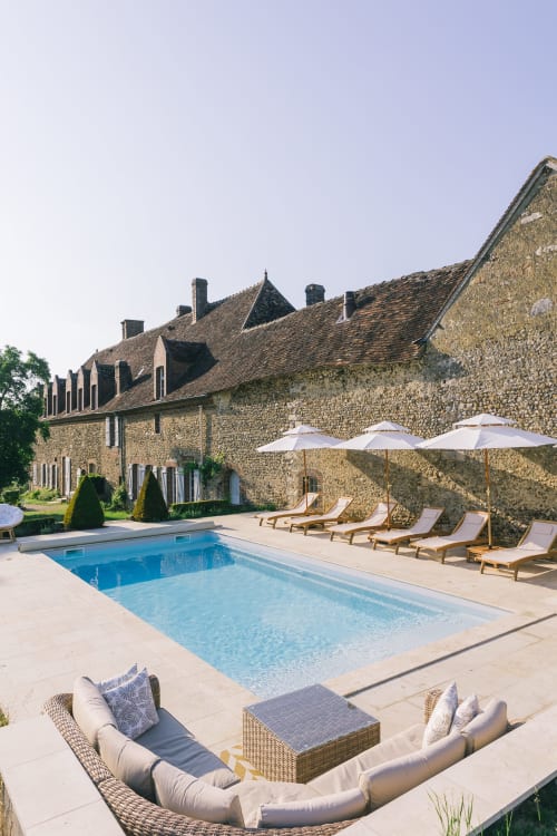 Le Prieuré Du Preux pool area with loungers, umbrellas, and historic stone manor in Sépeaux
