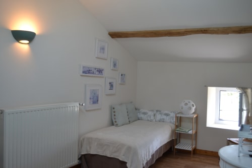 Bright bedroom at Logis De La Bénétière in Treize-Vents with bed, wooden beam, radiator, and garden views