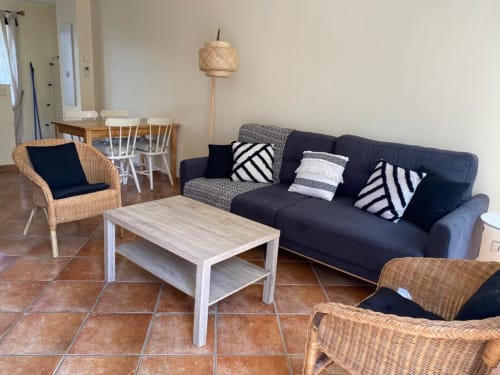 Séjour moderne de l'appartement duplex La Croix De La Jarrie avec canapé sombre, chaises en osier et table basse en bois clair
