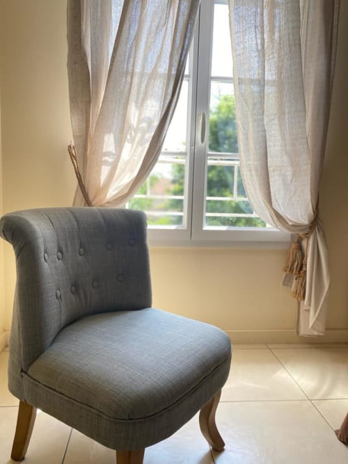 Grauer Polsterstuhl am Fenster mit leichten Vorhängen mit Blick auf den Garten des La Croix De La Jarrie B&B