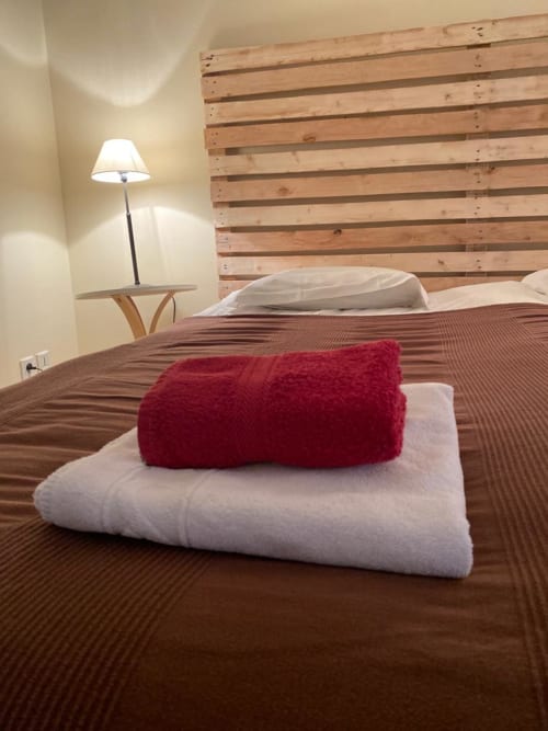 Modernes Schlafzimmer im La Croix De La Jarrie B&B mit Palettentkopfende, gefalteten weißen Handtüchern und Burgunderplaid
