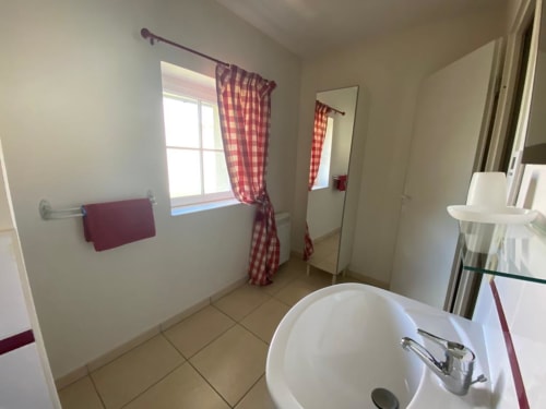 Badezimmer der 2-Zimmer-Duplexwohnung in La Croix De La Jarrie B&B, Châtres, mit Waschbecken, Fenster und roten karierten Vorhängen