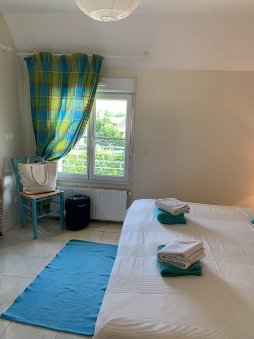 Helles Schlafzimmer im Gästehaus La Croix De La Jarrie mit zwei Betten, blauen karierten Vorhängen und Gartenblick in Châtres