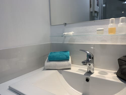 Modernes Waschbecken mit Chromarmatur, türkise und weiße Handtücher im La Croix De La Jarrie B&B in Châtres, Frankreich