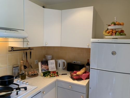Gut ausgestattete Küche im Apartment La Croix De La Jarrie mit weißen Schränken, beigefarbener Fliesenwand und frischen Produkten