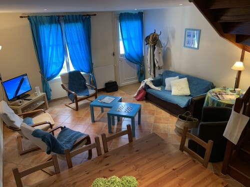 Séjour lumineux à la Guesthouse La Croix De La Jarrie à Châtres avec mobilier bleu, salle à manger et vue sur le jardin