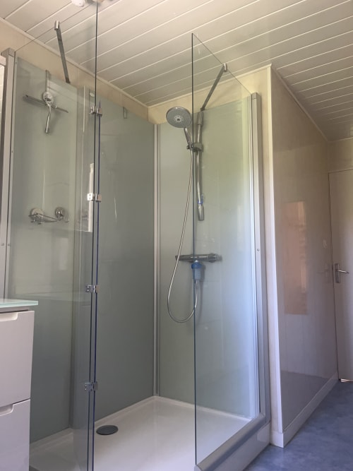 Modern glass shower enclosure with rainfall showerhead in La Conciergerie De Franck villa bathroom in Boissieres, France