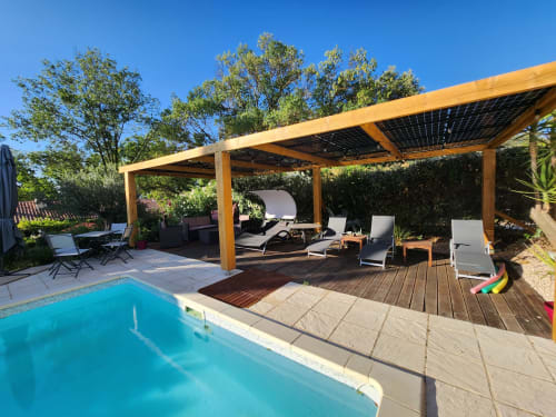 Patio au bord de la piscine du Domaine à l'Aise avec pergola en bois, chaises longues et piscine à Saint-Pargoire