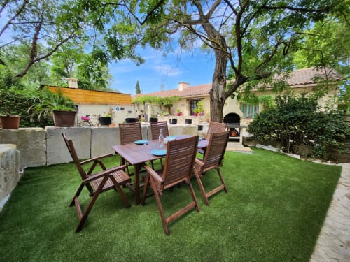 Garden view at Domaine à l'Aise cottage, Saint-Pargoire, with wooden dining table under shade trees and lush lawn