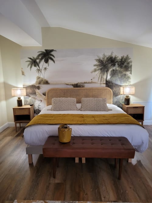 Chambre de luxe au Pavillon Des Millésimes avec tête de lit en rotin, fresque palmiers et touches dorées à Lussac