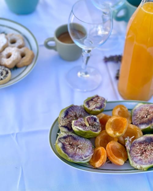 Colazione all'Agritusmo Stecadò con fichi freschi, agrumi, pasticcini, caffè e succo d'arancia su sfondo blu