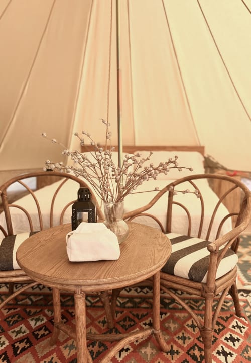 Interno rustico di una tenda a campana presso l'Agritusmo Stecadò con tavolo in legno, fiori secchi e sedie a righe a Dolceacqua