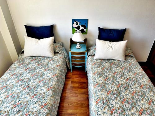 Dormitorio doble con ropa de cama floral y almohadas azul marino en apartamento de Baiona con vistas al mar