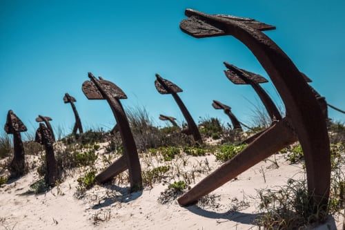 Ancres de navire rouillées exposées sur la plage de sable avec dunes herbeuses à Santa Luzia, Portugal