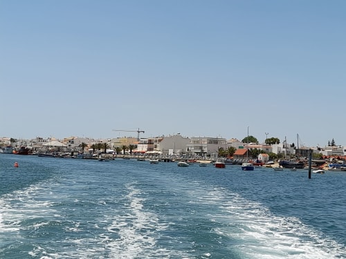 Vue sur le port de Santa Luzia avec bateaux, vagues bleues et bâtiments côtiers sous ciel dégagé