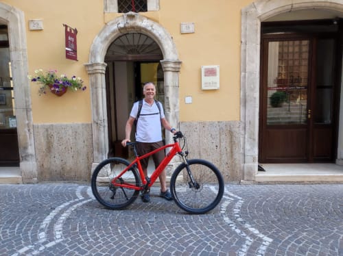 Homme avec un vélo rouge devant l'hôtel Stella CasaBono dans le centre historique de Sulmona, Italie