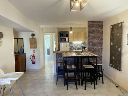 Offene Küche und Essbereich mit schwarzem Tisch, Backsteinakzentwand und modernen Geräten in den Gîtes des Trois