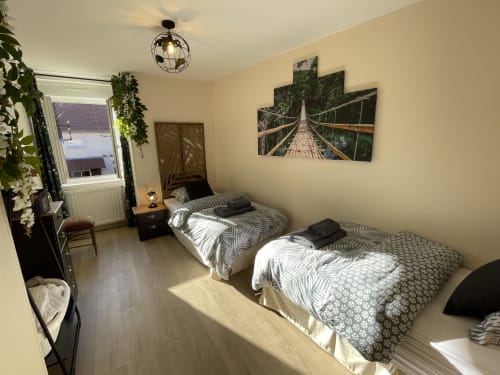 Gemütliches Zweibettzimmer in den Gites des Trois Provinces mit zwei Betten, Pflanzen und Waldbrücken-Kunstwerk in Saint Aignan