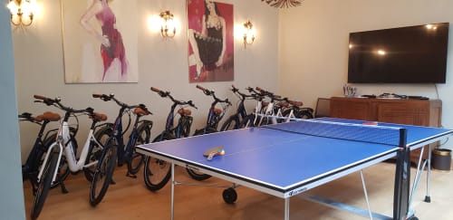 Salle de loisirs de l'hôtel Les Cabines à Houlgate avec table de ping-pong, vélos d'appartement et art mural