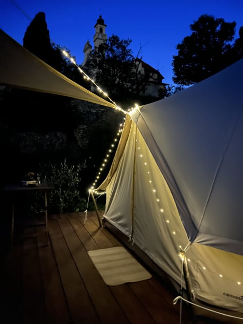 Tente glamping illuminée à l'Agritusmo Stecadò de Dolceacqua, guirlandes lumineuses, terrasse en bois et tour historique