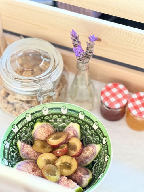 Pêches fraîches et figues dans un bol vert décoratifleur à l'Agritusmo Stecadò avec fleurs de lavande et confitures