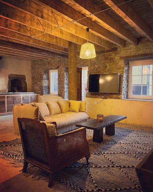 Warm rustic living room at Domaine du Tertre Ychot with exposed beams, stone walls, yellow sofa, and flat-screen TV