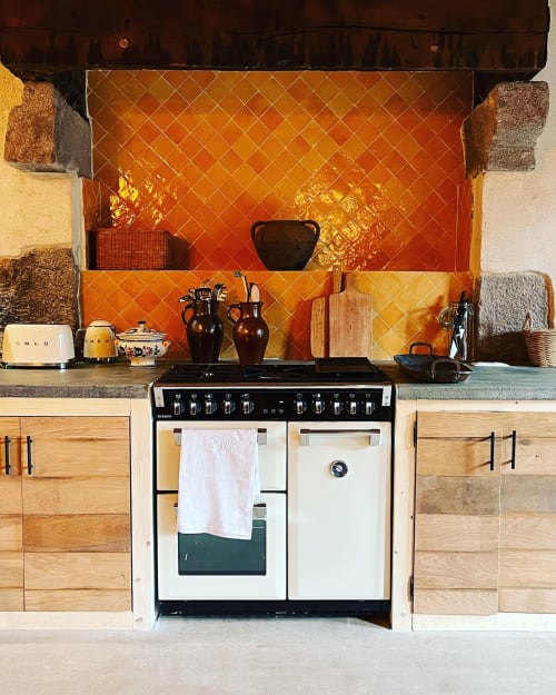 Modern kitchen with orange tile backsplash and black range cooker at Domaine du Tertre Ychot, Dol de Bretagne
