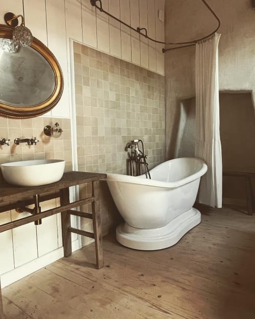 Rustic bathroom with freestanding white bathtub, wooden vanity, and cream tile walls at Domaine du Tertre Ychot, Dol de