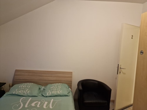 Chambre de la Résidence Mantekila BnB à Marcinelle avec lit, chaise noire et porte numérotée 2