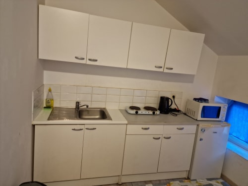 Petite kitchenette aménagée à la Résidence Mantekila avec évier, plaque de cuisson, micro-ondes et rangements blancs