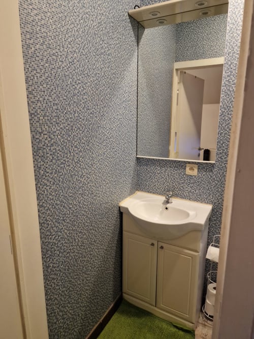 Salle de bain moderne avec carrelage mosaïque, meuble vasque blanc et miroir à l'appartement Résidence Mantekila à Marcinelle