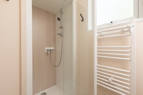 Salle de bains moderne avec douchette effet pluie et sèche-serviettes blanc chauffant, Camping La Lézardière
