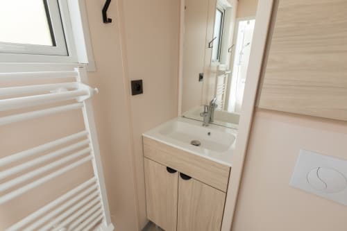 Salle de bain moderne avec vasque, miroir, porte-serviettes blanc et murs beige pêche à Camping La Lézardière