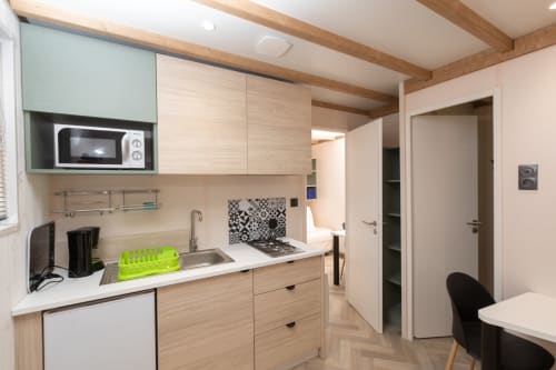 Kitchenette moderne à Camping La Lézardière, La Valette du Var avec meubles en bois, cuisinière à gaz et coin repas