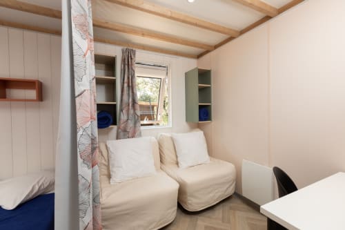 Chambre cosy avec lits jumeaux, poutres en bois, rangements et vue sur le jardin - Camping La Lézardière