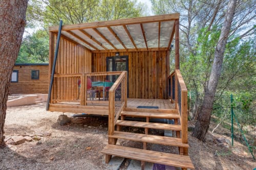 Élégante cabane de glamping en bois avec terrasse à Camping La Lézardière, nichée dans la verdure avec vue sur le jardin à La Valette du Var