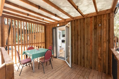 Véranda en bois avec table verte et chaises rouges au Camping La Lézardière, La Valette du Var, France