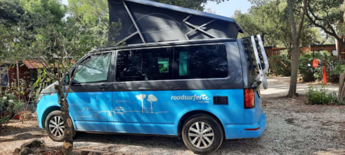 Camping-car bleu avec toit relevable au Camping La Lézardière à La Valette du Var, garé sous les arbres