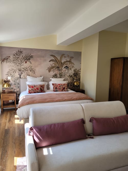 Elegant bedroom at Pavillon Des Millesimes with botanical wallpaper, queen bed, coral bedding, cream sofa, and wooden