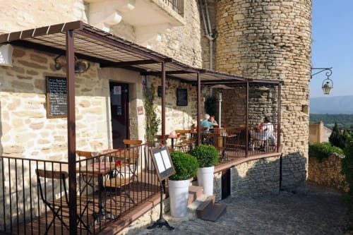 Terras van Provence Km28 guesthouse in Gordes met stenen architectuur, overdekt zitgedeelte en uitzicht op het platteland