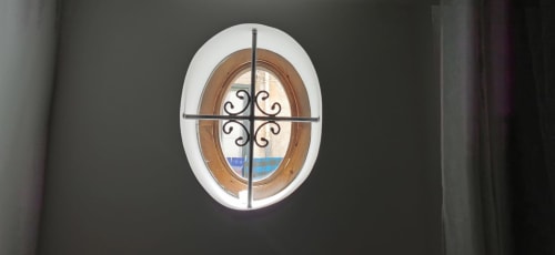 Oval window with decorative iron grille in Casa Bellini apartment, Palermo overlooking city views