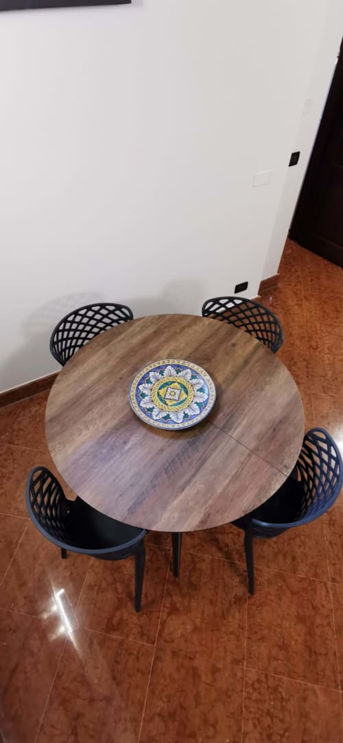 Overhead view of round dining table with decorative ceramic plate at Casa Bellini apartment in Palermo, with black mesh