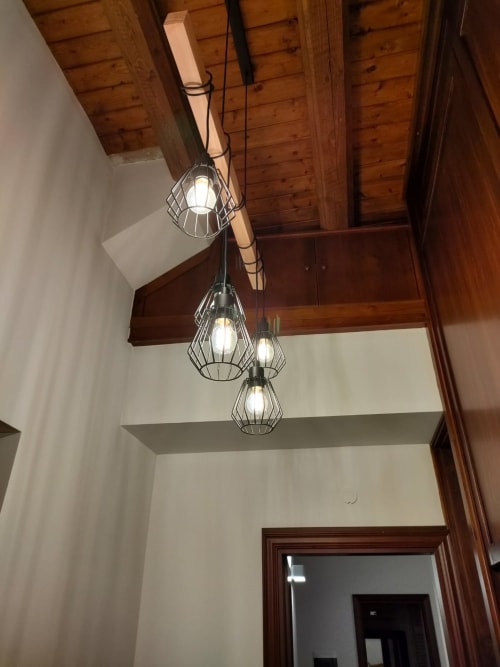 Modern pendant lights hang from wooden ceiling beams in Casa Bellini apartment, Palermo hotel entryway with white walls and