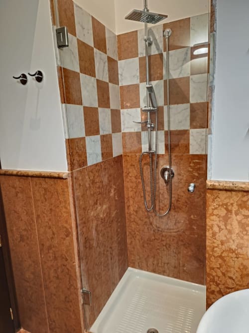 Modern shower enclosure with brown and white checkered tile backsplash at Casa Bellini apartment in Palermo