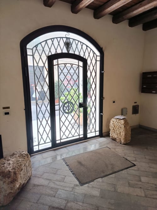 Ornate black arched entrance door with diamond lattice pattern at Casa Bellini apartment in Palermo