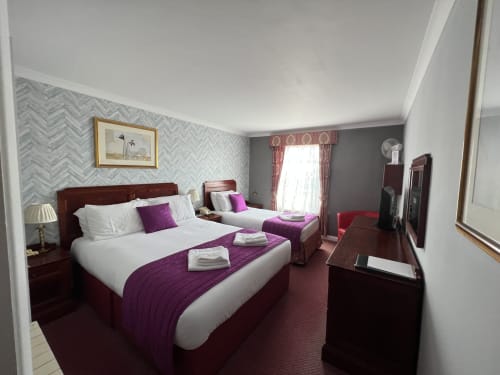 Treble Room at La Trelade Hotel with two beds, purple throws, herringbone wallpaper, and modern amenities in St Martins